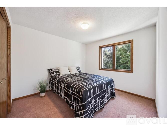 A bedroom with a bed, pillows, a potted plant, and a window.