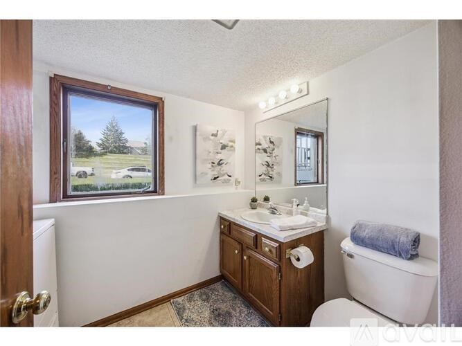 A bathroom with a white tub, wooden vanity, and a window.