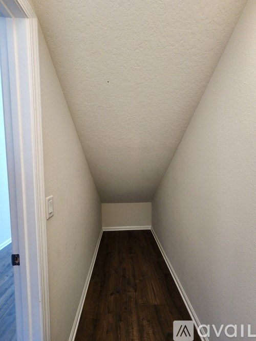 A long hallway with wood floors and white walls.