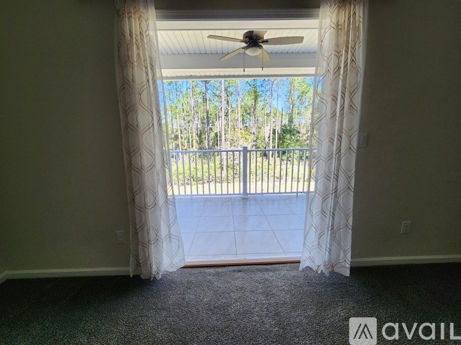 A room with a carpeted floor and a ceiling fan.