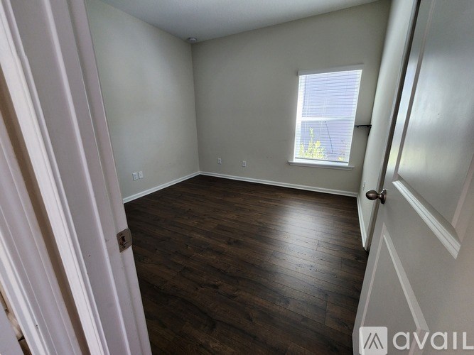 A room with wooden flooring and a window with blinds.