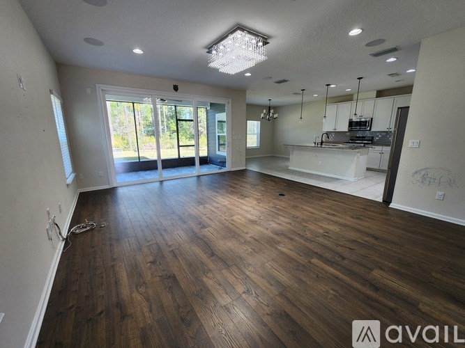 A spacious room with wooden flooring and a large window.