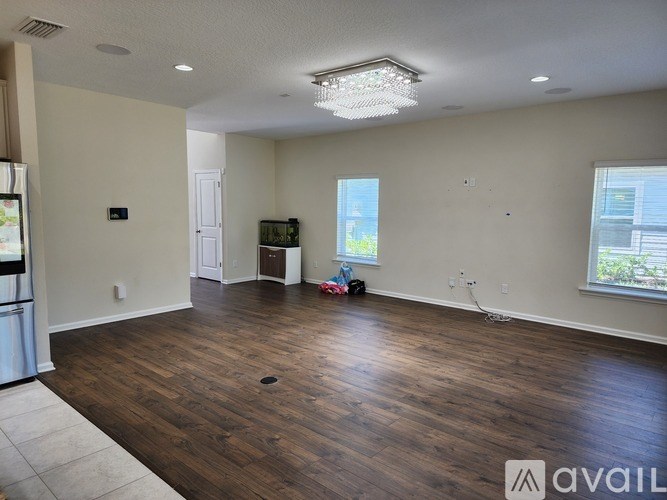 A large empty room with wooden floors and a chandelier.