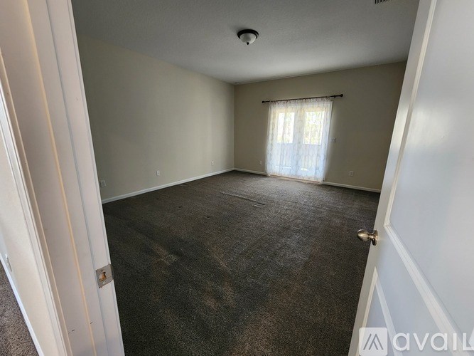 A room with a carpeted floor and a window with curtains.