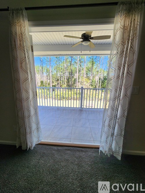 A balcony with a fan and a view of trees.
