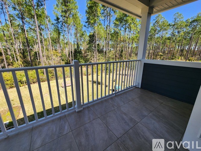 A balcony with a white railing overlooks a grassy area with trees.