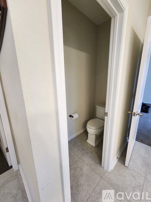 A bathroom with a toilet and a doorway leading to another room.