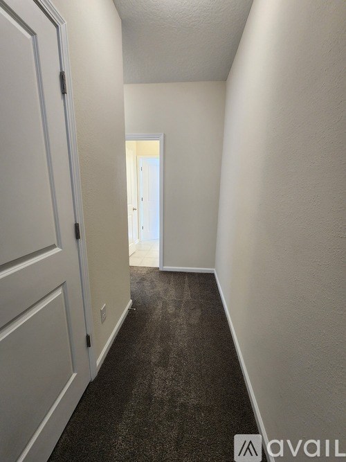 A hallway with a carpeted floor and white walls.