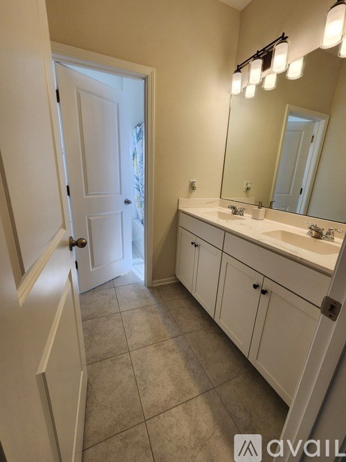 A bathroom with a white door, sink, and cabinets.
