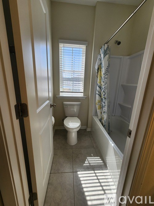 A bathroom with a toilet, a shower, and a window.