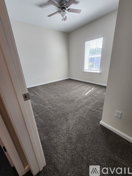 A room with a ceiling fan and a window with blinds.