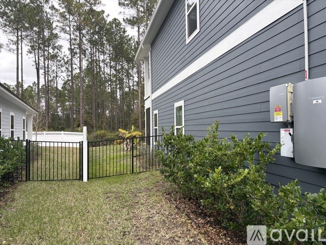 A house with a blue siding and a white door is surrounded by a black fence.