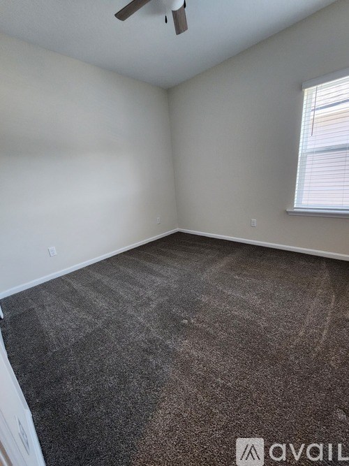 A room with a carpeted floor and a window with blinds.