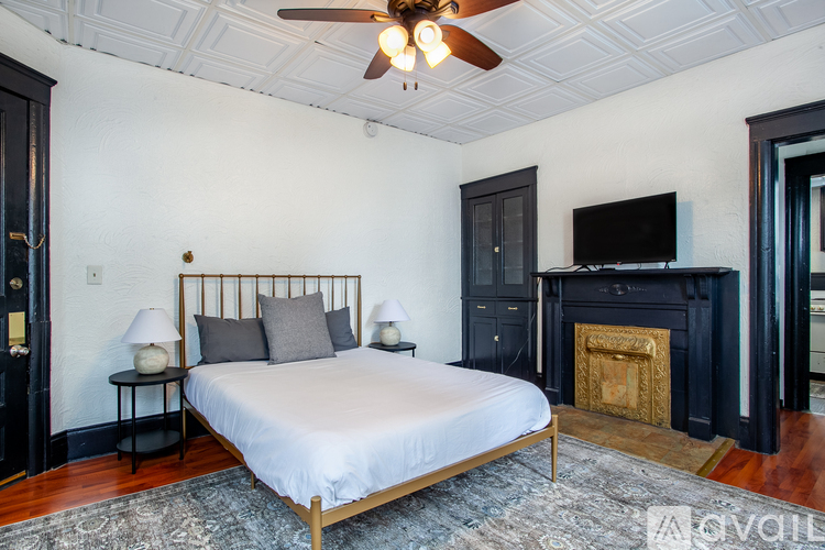 A bedroom with a bed, a fireplace, and a ceiling fan.