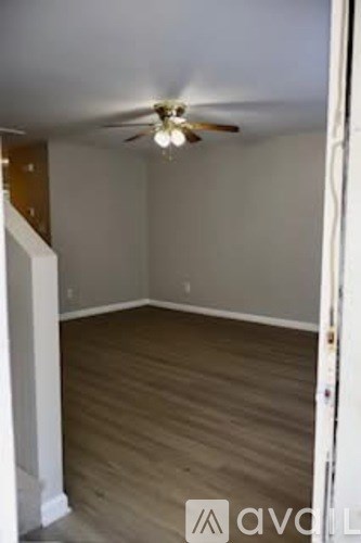A room with a ceiling fan and wooden flooring.