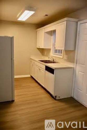 A kitchen with white cabinets and a wooden floor.