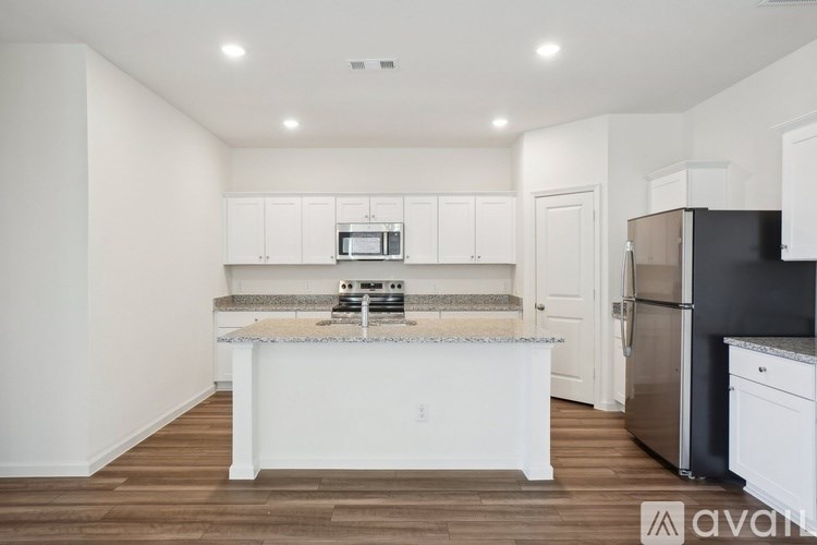 A kitchen with white cabinets and a black refrigerator.