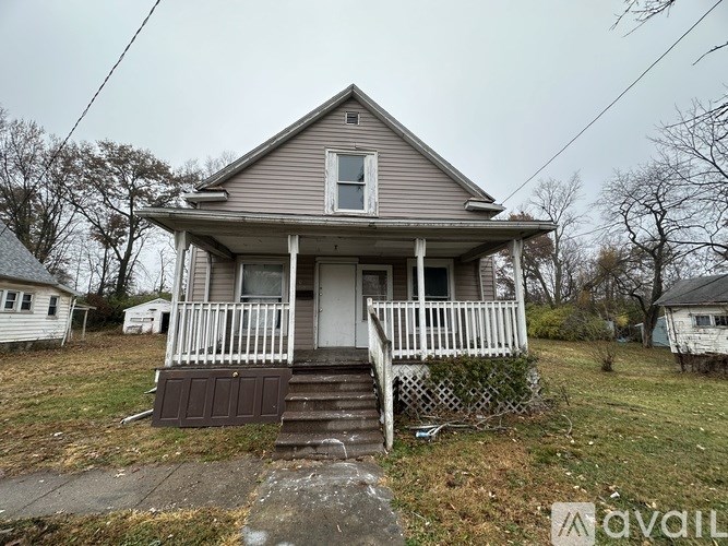 A small, two-story house with a front porch and a brown door.