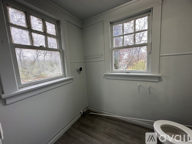 A room with two windows and a wooden floor.