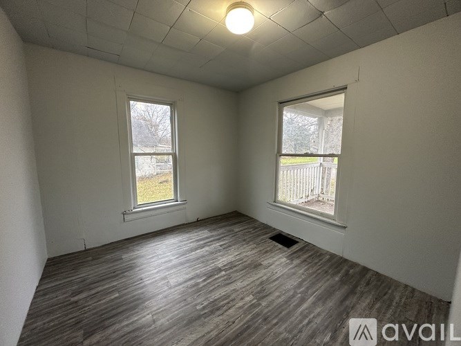 A room with a window and a wooden floor.
