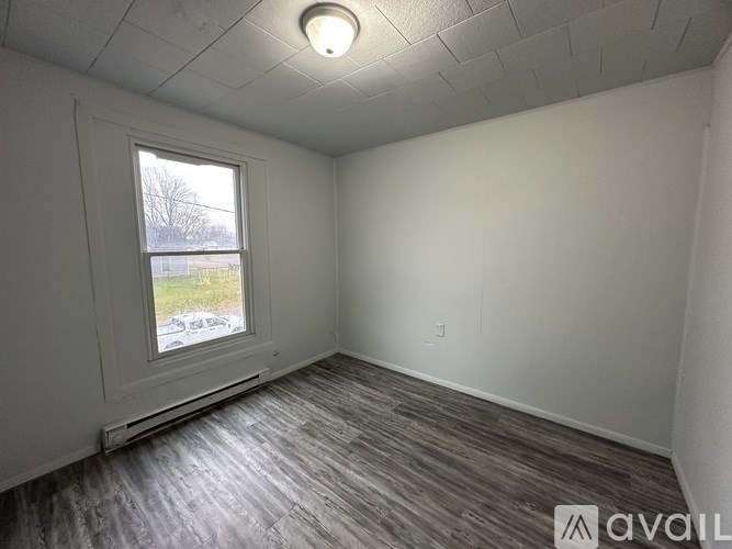 A room with a window and a wooden floor.