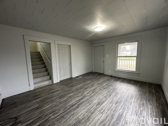 A room with wooden flooring and a window with blinds.