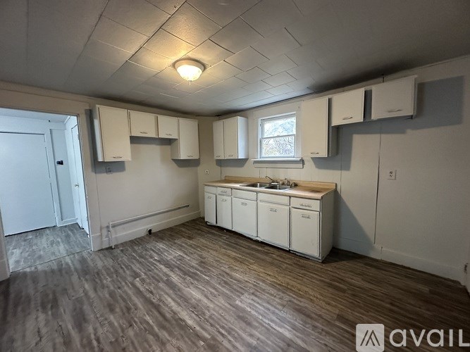 A kitchen area with a sink, cabinets, and a window.