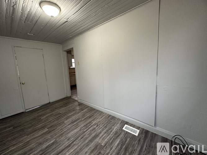 A room with a white door and a wooden floor.