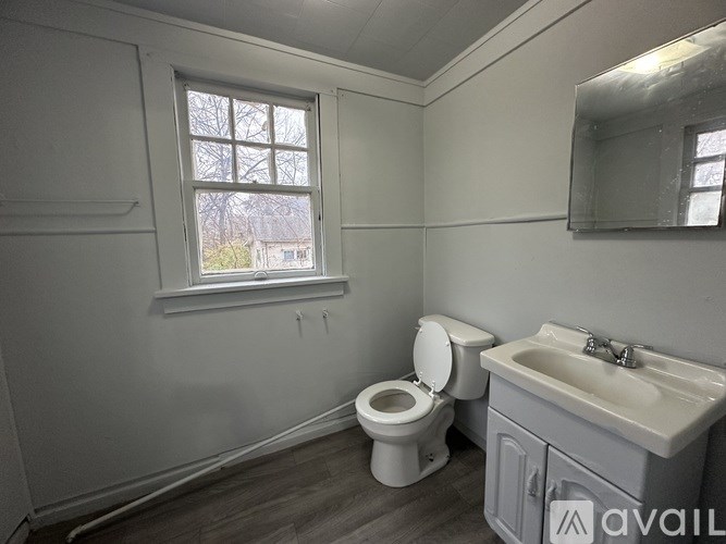 A bathroom with a toilet, sink, and window.