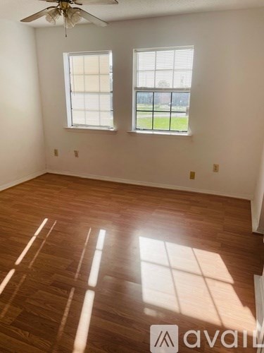 A room with wooden floors and two windows.