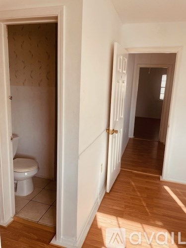 A hallway with a toilet visible through an open door.
