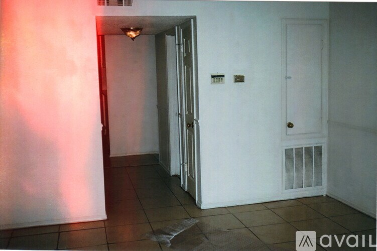 A hallway with a door on the right and a wall-mounted light fixture.