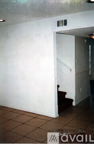 A white doorway leads to a hallway with a staircase.