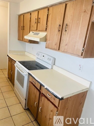 A kitchen with wooden cabinets and a white stove top oven.