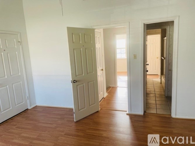A room with white walls and wooden floors, with a door on the left and another door on the right.