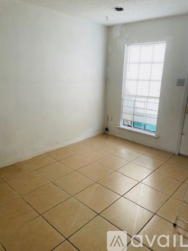 A room with a tiled floor and a window with blinds.