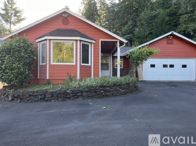 A red house with a white garage door and a stone wall in front.