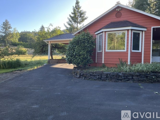 A red house with a stone wall and a gravel driveway.