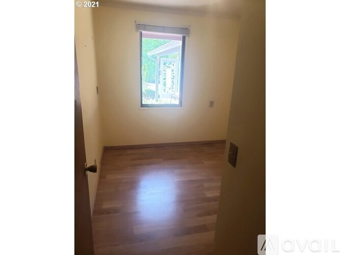 A room with a window and wooden flooring.