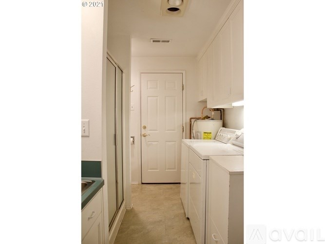 A small kitchen with a white door and a white fridge.
