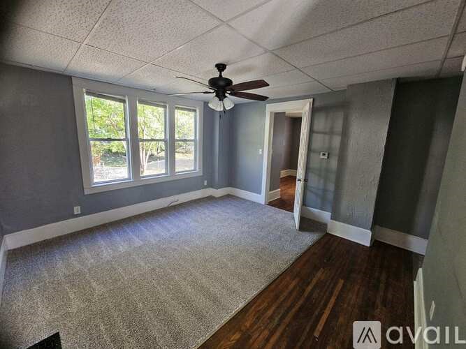 A room with a ceiling fan and a rug on the floor.