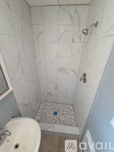 A bathroom with a marble tile shower and a white sink.
