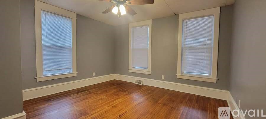 A room with wooden floors and three windows.