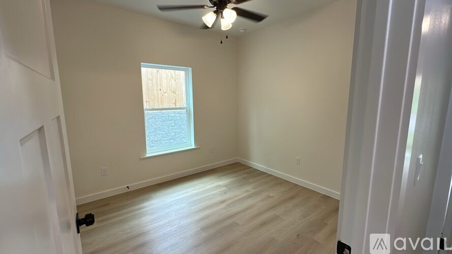 A room with a ceiling fan and a window overlooking a body of water.