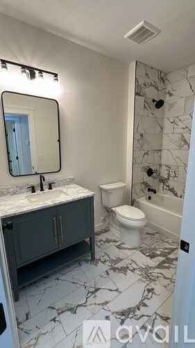 A bathroom with marble tiles and a white toilet.