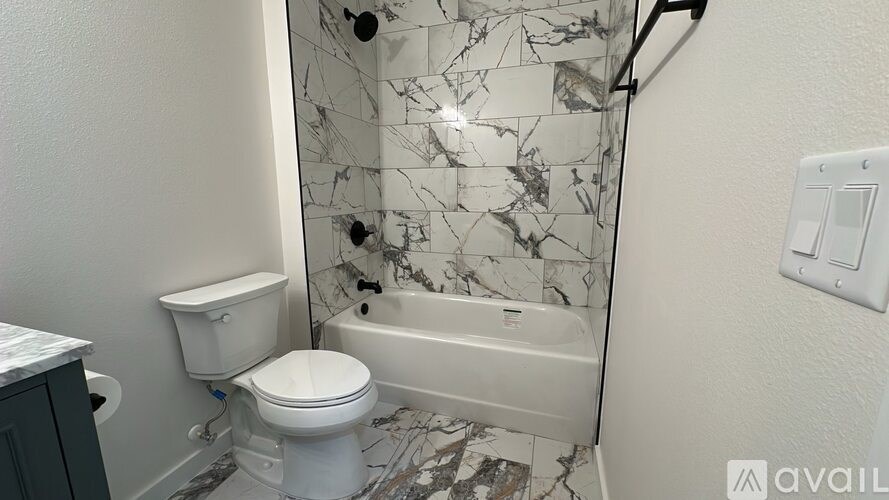 A bathroom with a toilet, tub, and marble tiles.