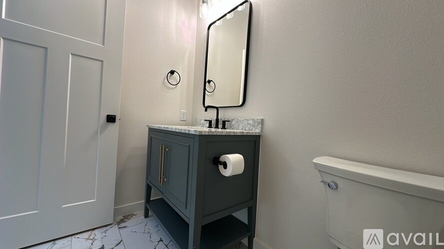 A bathroom with a white tub, a grey cabinet, and a white door.