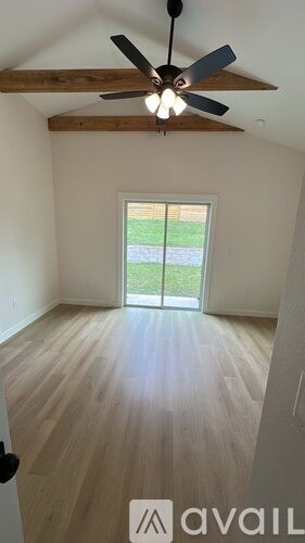 A room with a ceiling fan and a sliding glass door.