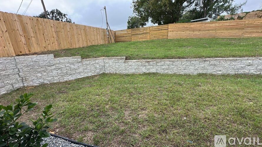 A backyard with a stone wall and wooden fence.