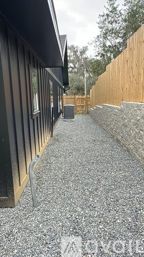 A gravel pathway leads to a wooden fence and a house.